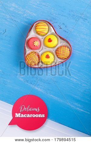 Macaroon cakes. Colorful almond macaron cookies. Love heart-shaped delivery box. Different flavors. On blue wooden rustic background.