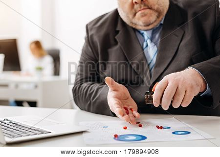 One pill at a time. Persistent awkward big guy trying taking his daily dose of medication while having a break at the office