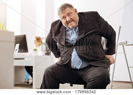 My knees hurt. Helpless overweight middle aged man feeling unable standing up after working long hours sitting at the desk