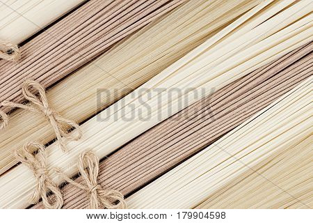 Raw japanese noodles different kind with decoretive bows top view. Border with copy space.