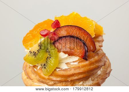 Closeup of cake with fresh fruits isolated on gray background.
