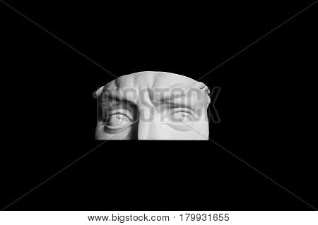 Plaster form parts of the upper part of human face. A fragment of the eye of the sculpture to visualize. Art sculpture isolated on black background. The face men white surround.