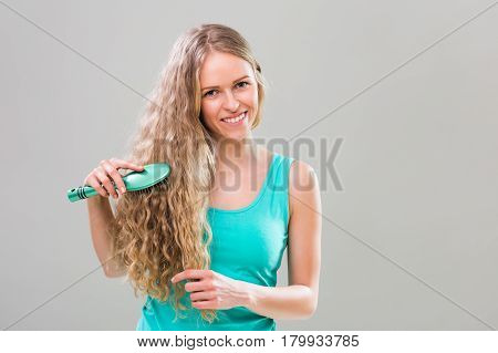 Young woman brushing her gorgeous long blonde hair.