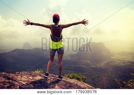 cheering young woman trail runner enjoy the view on sunrise mountain peak