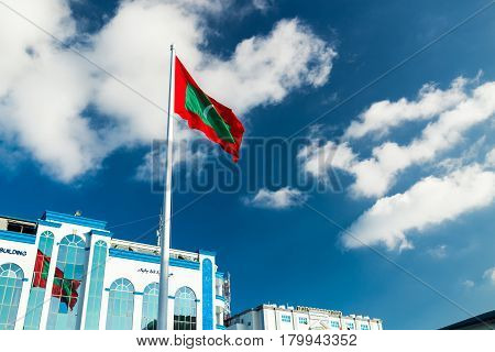 Male, Maldives - December 17, 2016: Shaheedh Hussain Adam Building And Flag Of Maldives In Centre Of