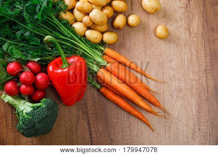 Potatoes with carrot and pepper. Red radish, brocoli and raw new potato. Fresh natural vegetables. Organic bio food. On wooden table.