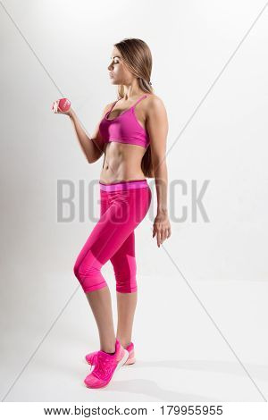 Woman In Sportswear Is Engaged In Fitness. In The Hands Holding Dumbbells. Photo Studio.