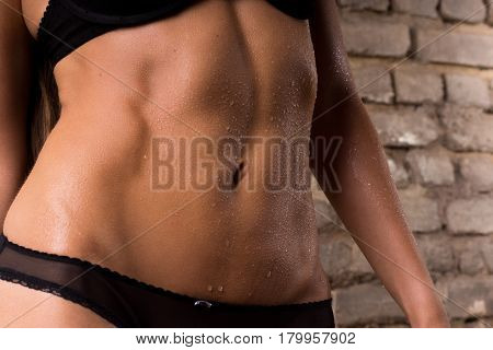 Female slender belly аgainst a brick wall background