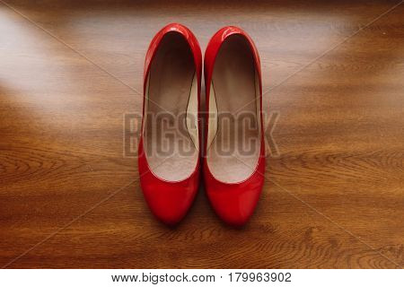 Stylish red women's shoes on wooden floor elegant bride's shoes closeup on rustic background morning wedding preparation