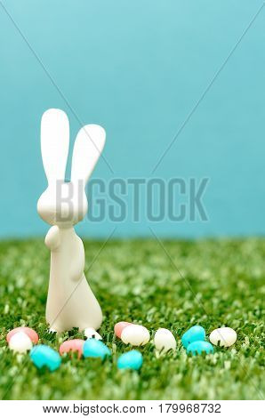 A white plastic bunny figurine displayed with jelly beans