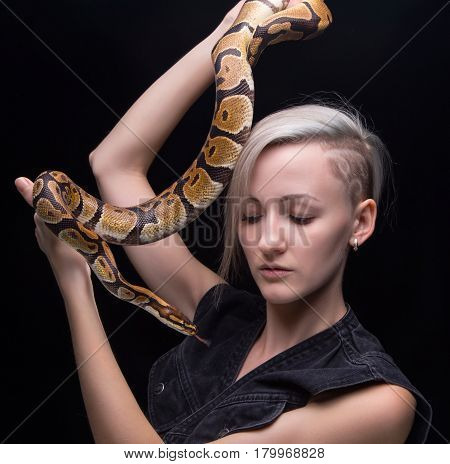 Blond woman with snake on black background