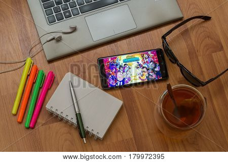 Nitra, Slovakia, april 3, 2017: Animation Throwdown application in a mobile phone screen. Workplace with a laptop, an earphones, notepad, pen, tea, sunglasses and color markers on wooden background