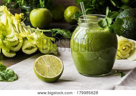 Detox diet. Green smoothie with different vegetables on wooden background.