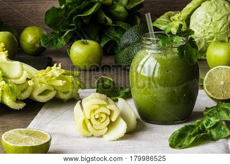 Detox diet. Green smoothie with different vegetables on wooden background.