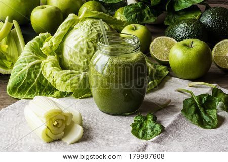 Detox diet. Green smoothie with different vegetables on wooden background.