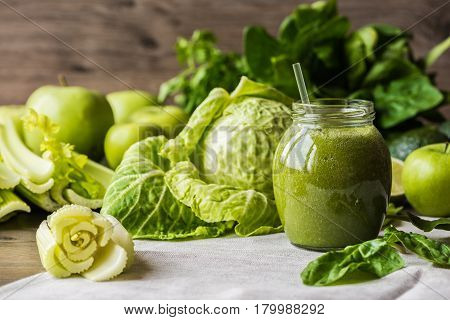 Detox diet. Green smoothie with different vegetables on wooden background.