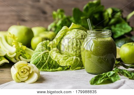 Detox diet. Green smoothie with different vegetables on wooden background.