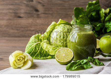 Detox diet. Green smoothie with different vegetables on wooden background.