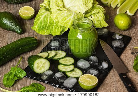 Detox diet. Green smoothie with different vegetables on wooden background.
