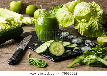 Detox diet. Green smoothie with different vegetables on wooden background.