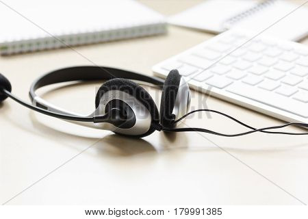 operator headset and computer keyboard on workdesk for call center concept on beige background