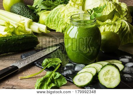 Detox diet. Green smoothie with different vegetables on wooden background.
