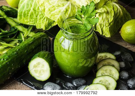 Detox diet. Green smoothie with different vegetables on wooden background.