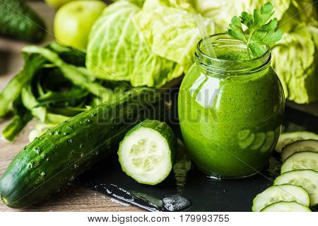 Detox diet. Green smoothie with different vegetables on wooden background.