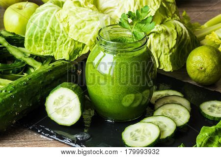 Detox diet. Green smoothie with different vegetables on wooden background.