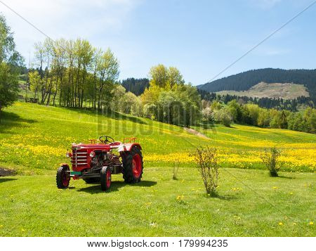 Surselva Switzerland - May 14 2015: Antique tractor parked on a lawn. The tractor is illuminated by the sun during a beautiful day on the day of the Feast of the Ascension.