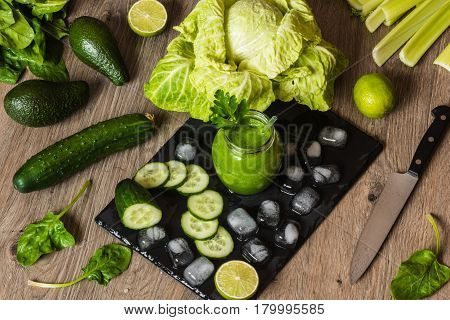 Detox diet. Green smoothie with different vegetables on wooden background.
