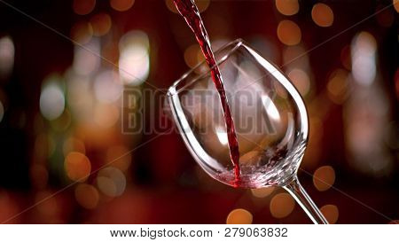 Freeze motion of pouring red wine from bottle into goblet. Low depth of focus