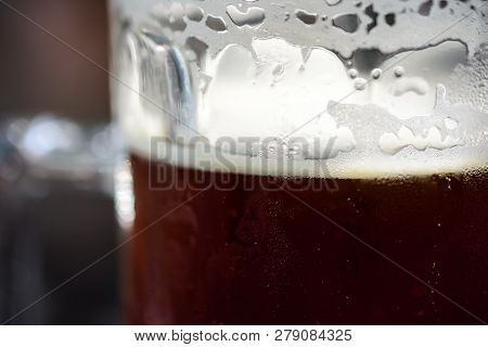 Refreshing Cold Glass Of Dark Beer With Condensation, Foam And Bubbles