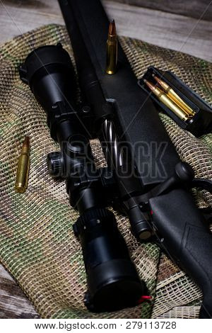 The Black Rifle With Ammo And Scope On The Multicam Background. Close Up.