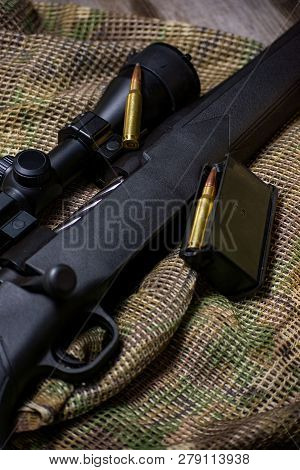 The Black Rifle With Ammo And Scope On The Multicam Background. Close Up.