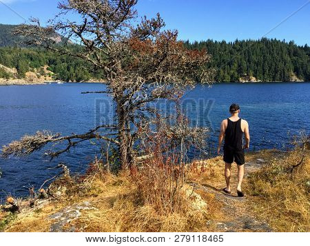 A Young Man Walking Along The Path Of The Small Alexander Island Overlooking The Ocean Of West Bay A