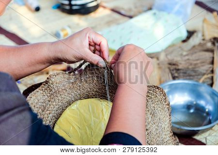 Close-up Hands Of Thai Female Artisans Is Using A Needle Weaving Sew Hat That Woven Comes From Plant
