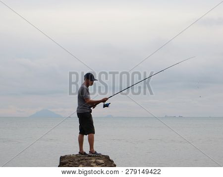 Anyer, Indonesia - June 25, 2018: A Man Arranged His Fishing Line On The Edge Of The Sea.