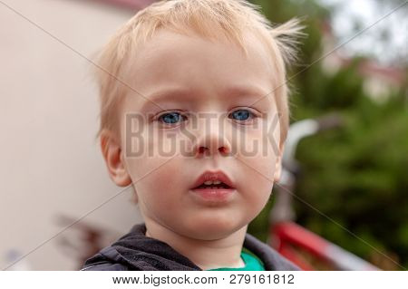 Close Up Portrait Of Cute Caucasian Baby Boy With Serious Expression In Blue Eyes. Fair Hair. Strong