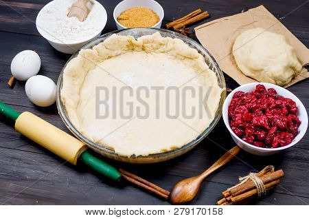 Pie Base In A Glass Round Form And Ingredients For Making Cake  - Flour, Egg, Cherry, Brown Sugar, C