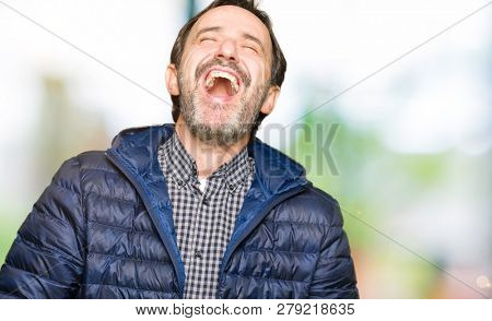 Middle age handsome man wearing winter coat Smiling and laughing hard out loud because funny crazy joke. Happy expression.