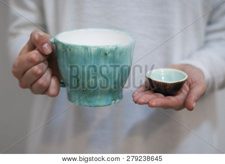 Ceramic Mugs On The Background Of Pastel Colors In The Hands Of A Woman