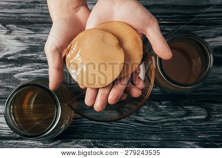 Top View Of Bottled Tea And Kombucha Mushrooms In Hands