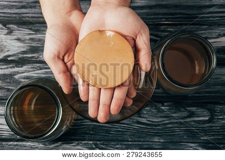 Top View Of Bottled Tea And Kombucha Mushroom In Hands