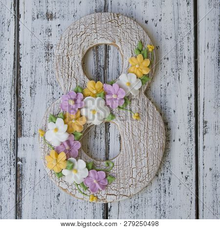 Cookie Covered With Glaze Made In A Form Of Number Eight With Sring Flowers On White Wooden Backgrou