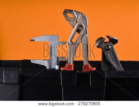 Garage Plastic Tool Box With Working Tools Isolated On An Orange. Nippers, Wrench, Caliper