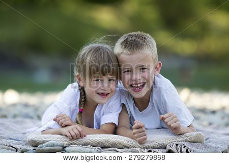 Two Young Happy Cute Blond Smiling Children, Boy And Girl, Brother And Sister Laying Embraced On Peb