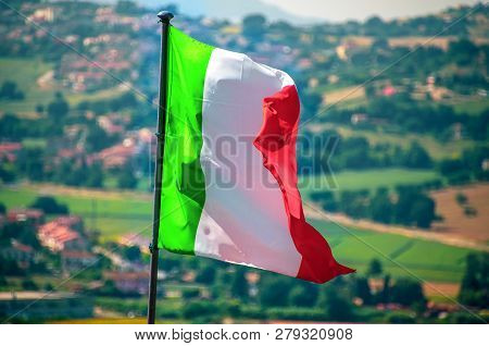 A Waving Italian Flag Wave Countryside In Background .