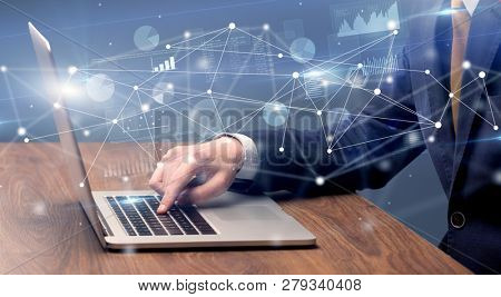 Businessman typing on laptop with linked reports charts grapghs around
