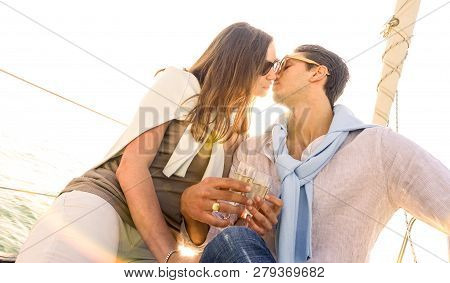Rich Young Couple In Love On Sailboat Kissing At Sunset - Luxury Lifestyle Concept Sailing Around Wo